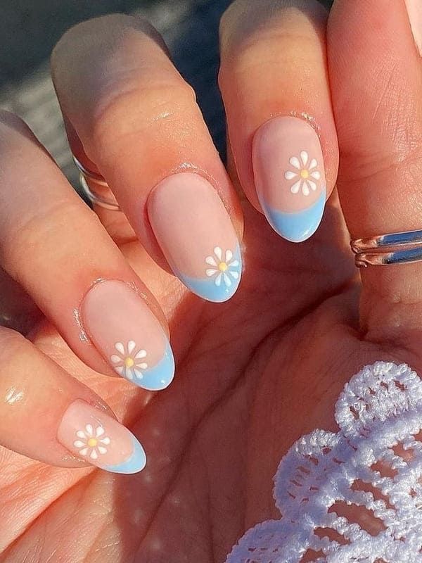 Playful Floral French Tip Nails: Soft Pink Base with Delicate Blue Tips and Charming White Daisies for a Spring/Summer Aesthetic.