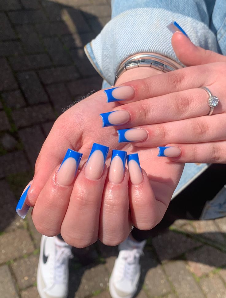 Chic Nail Design: Playful Nude and Vibrant Blue French Tips with Curved Patterns.