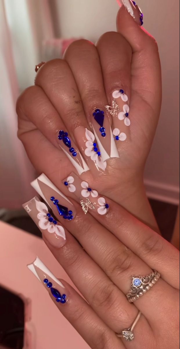 Sophisticated White and Blue Floral Nail Design with Glamorous Gem Accents.