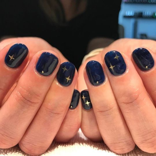 Celestial-Inspired Nail Design: Glossy Deep Navy with Delicate Gold Stars for Elegance and Whimsy.