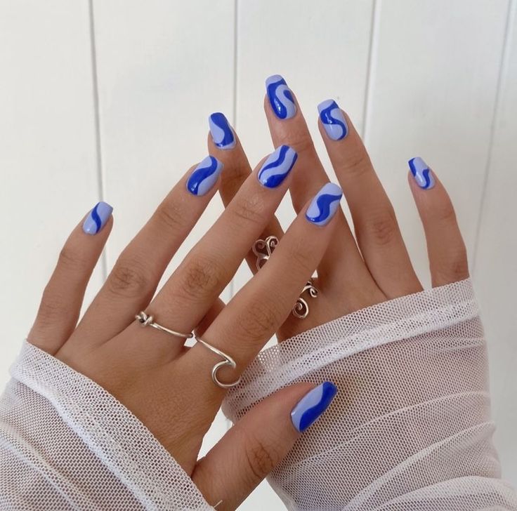 Refreshing Bold Blue Nail Design with Curved White Accents for a Chic Look.