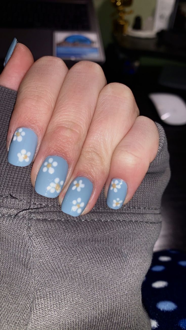 Charming Matte Blue Nails with Delicate White Floral Designs for a Whimsical Touch.