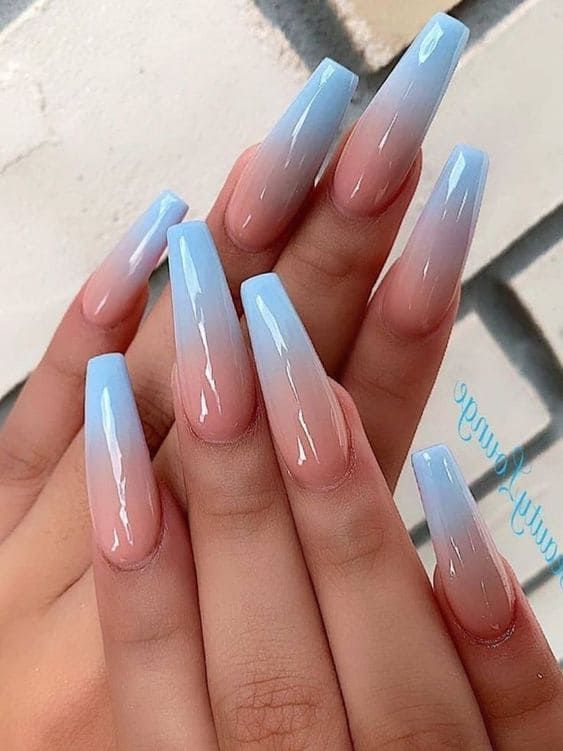 Elegant Ombre Nail Design: Light Blue to Subtle Pink Gradient in a Chic Elongated Shape.