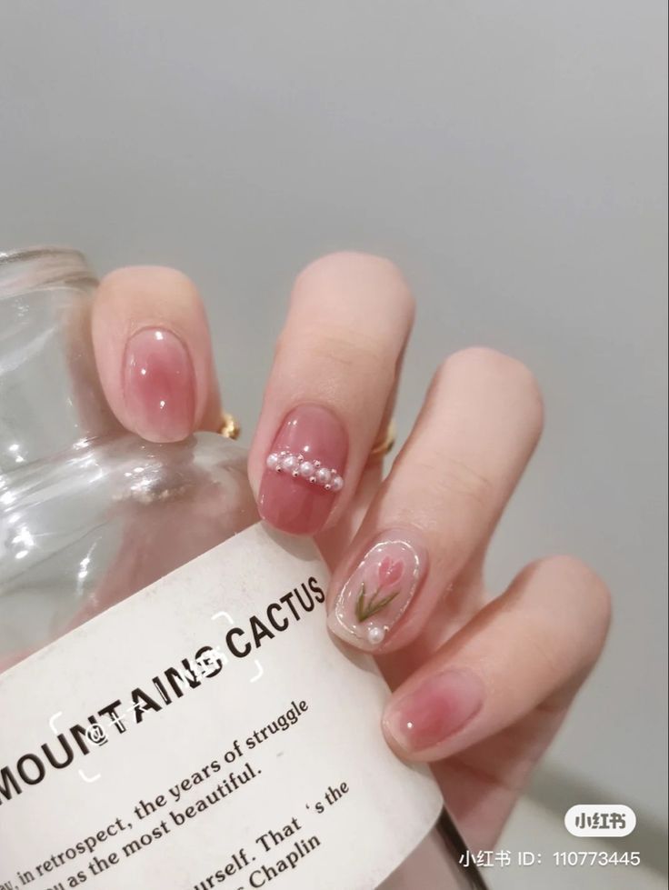 Sophisticated Nail Design: Soft Pink and Nude Shades with Pearl and Floral Accents.