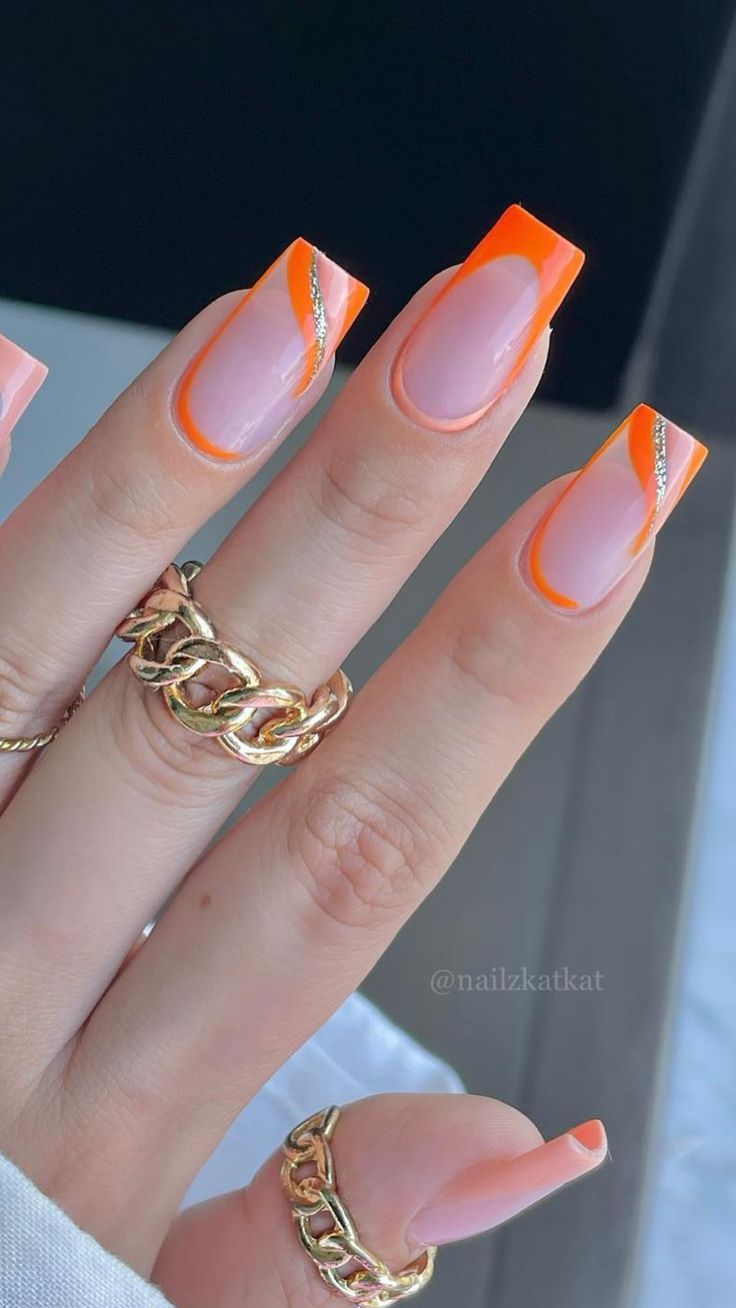 Modern Elegant Nail Design: Soft Pink and Bold Orange Tips with Silver Accents