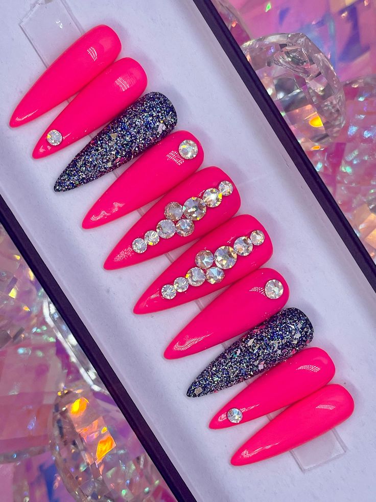 Glamorous Pink Stiletto Nails with Black Glitter and Rhinestones for a Bold Statement.