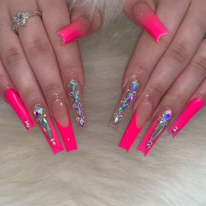 Glossy Vibrant Pink Acrylic Nails with Intricate Rhinestone Designs on a Nude Base.