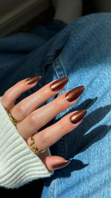 Chic Brown Stiletto Nails Enhance Casual Denim and Sweater Ensemble with Metallic Shine and Gold Accents