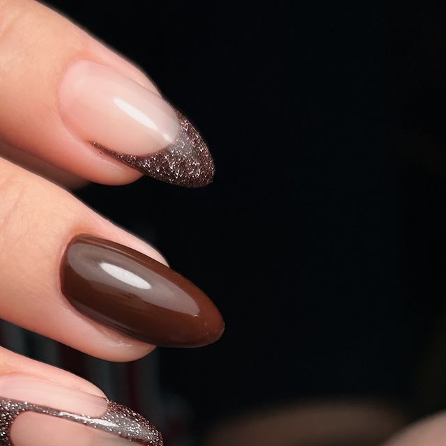 Sophisticated Nail Design: Glossy Dark Brown and Nude Shades with Glittery Tips.