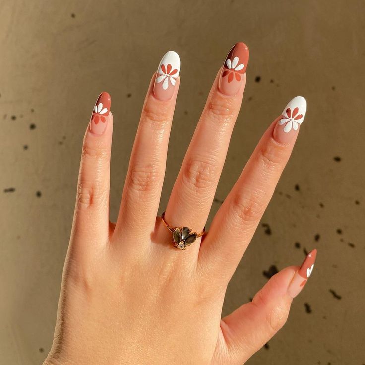 Chic Nail Design: Modern Brown and White Tips with Playful Floral Accents.