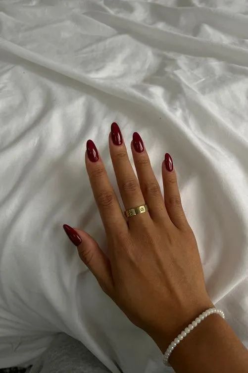 Chic Burgundy Nail Design with Almond-Shaped Tips and Minimalist Accessories for Sophisticated Elegance.