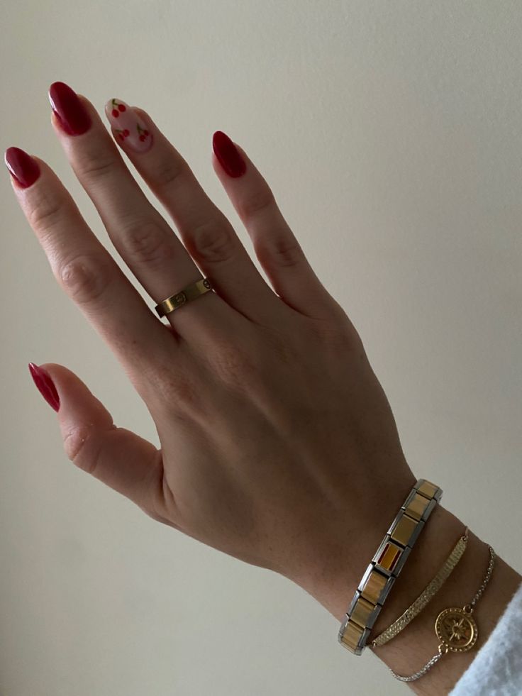 Sophisticated Nail Design: Deep Red Polish with Creamy Accent, Complemented by Chic Bracelets.