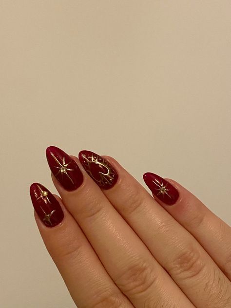 Elegant Red Almond-Shaped Nail Design with Gold Accents and Star Embellishments.