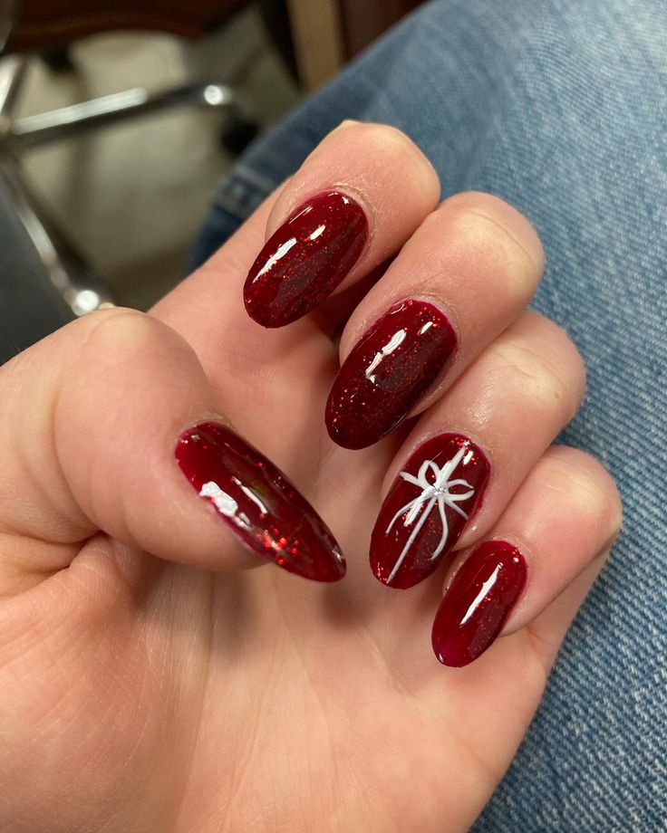 Elegant Glossy Red Nails with Shimmering Finish and Charming White Bow Design for Special Occasions.