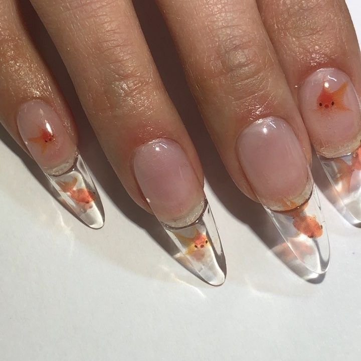 Playful Aquatic-Themed Nail Design with Long Clear Coffin Tips and Delicate Orange Fish Motifs.