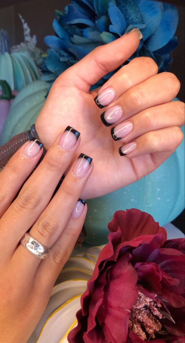 Chic Black-Tipped Nail Design with Floral Backdrop for Understated Glamour.