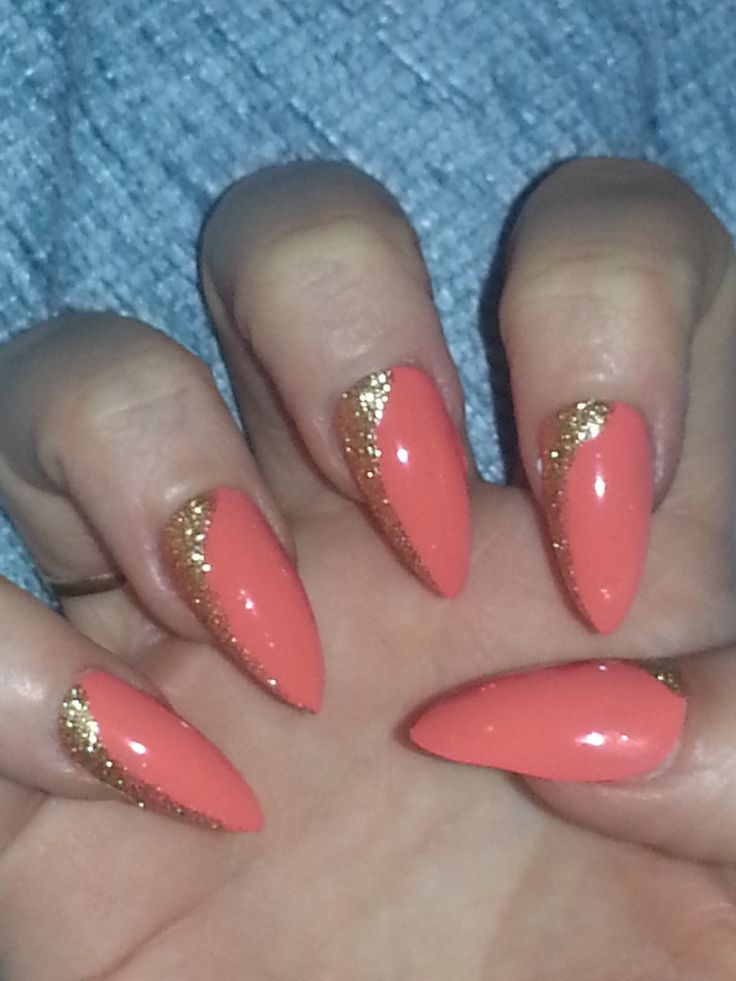 Vibrant Coral Stiletto Nails with Glamorous Gold Glitter Accent for a Stunning Statement Manicure.