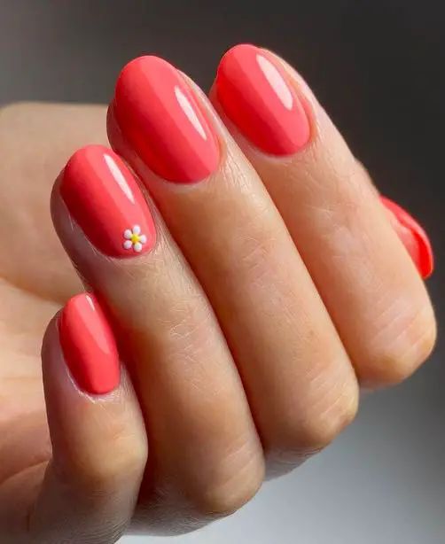 Cheerful Coral Nail Design with Glossy Finish and Whimsical Floral Accent