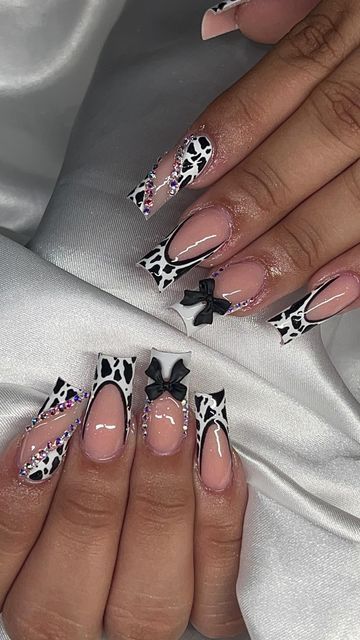 Chic Black and White Cow Print Nail Design with Sparkling Embellishments and Playful Bows