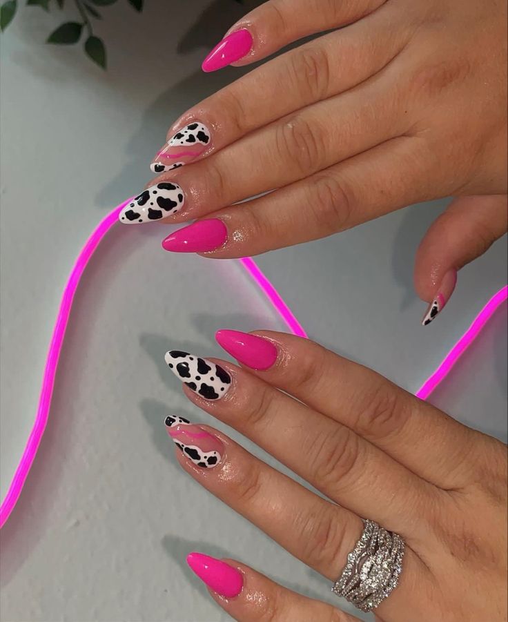 Playful Pink and Black-and-White Almond-Shaped Nail Design with Whimsical Cow Print Accents.