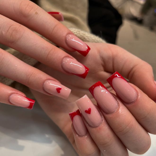 Chic Nude and Bold Red French Tip Nail Design with Heart Motifs