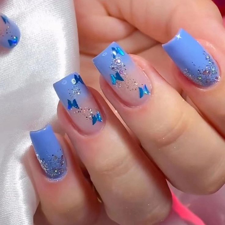 Whimsical Blue Gradient Nail Design with Glitter and Playful Bows.