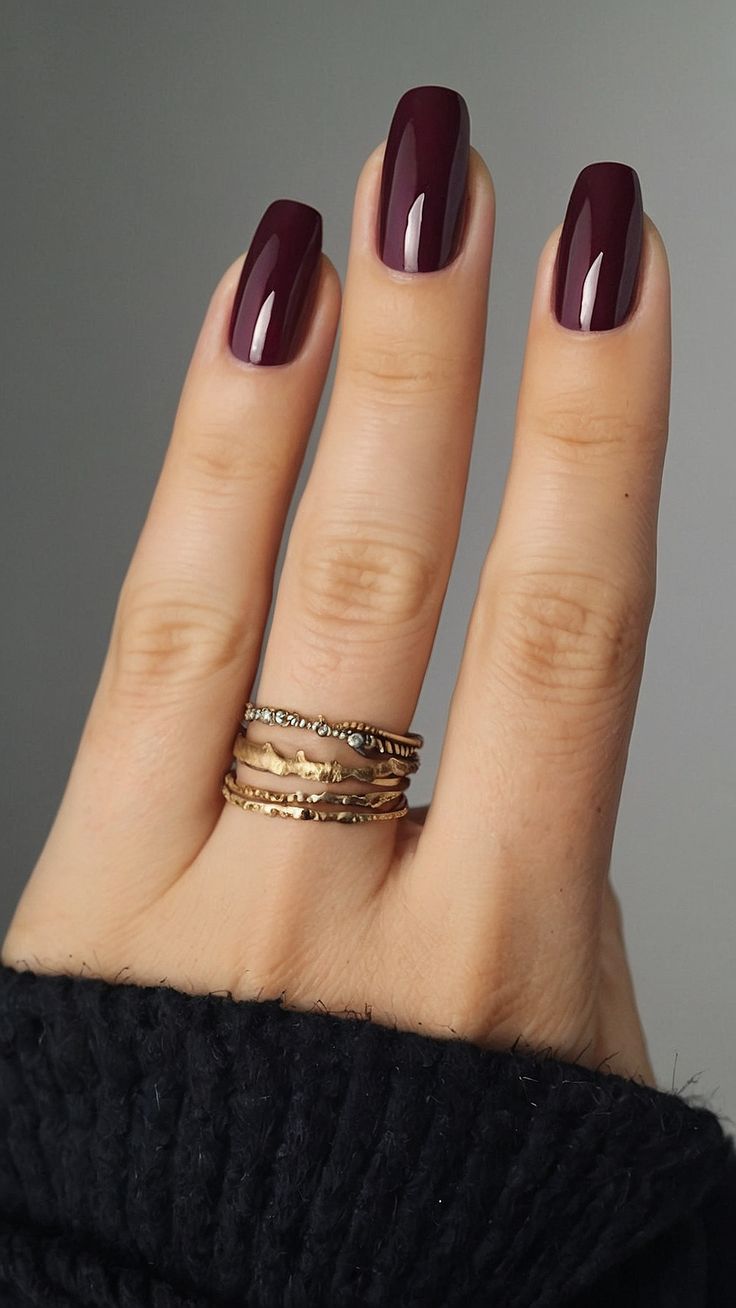 Sophisticated Deep Burgundy Nails with Glossy Finish and Glamorous Gold Rings.