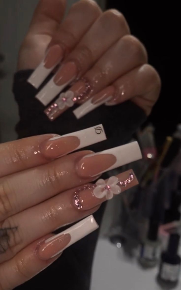 Sophisticated Nail Art: Long Square Nails with Nude Base, White Tips, Pink Glitter, and Floral Accents.