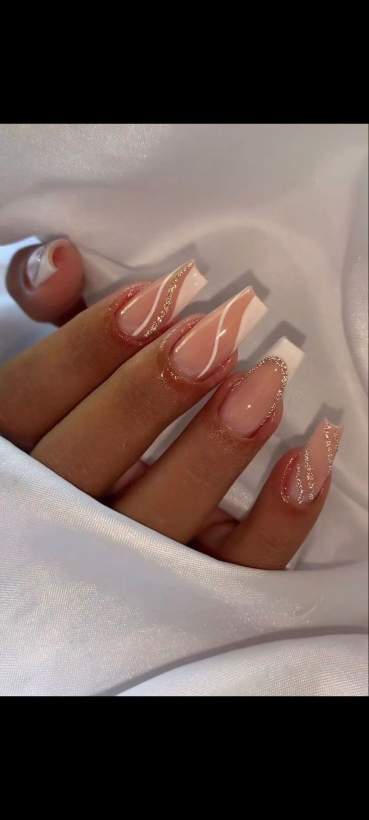 Chic Nude and White Nail Design with Wave Patterns and Glitter Accents.