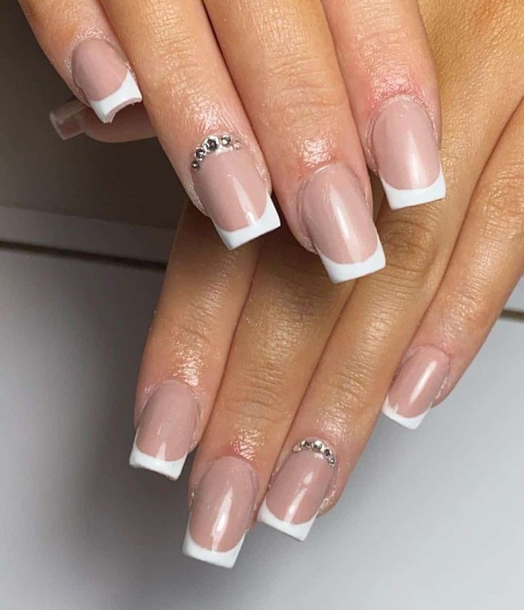 Chic Elegant French Manicure: Nude Base, Classic White Tips, and Glamorous Rhinestones.