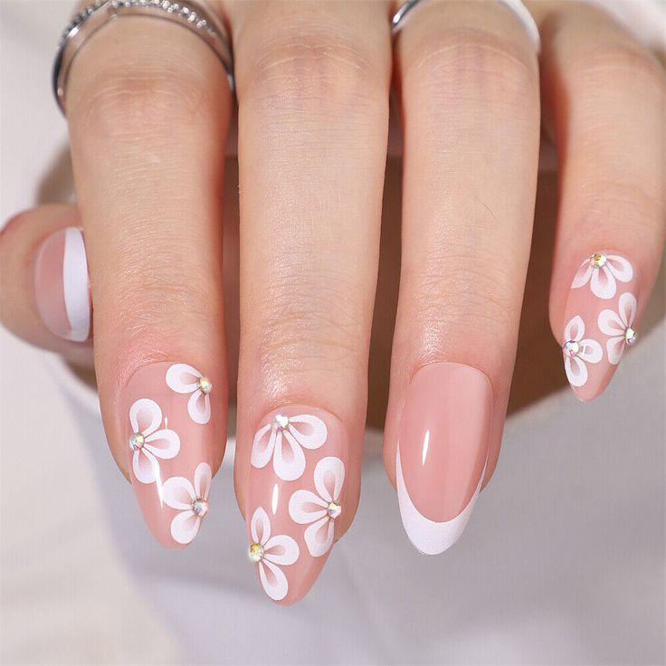 Elegant Floral Nail Design Featuring Delicate White Flowers and French Tips on a Soft Pink Base.