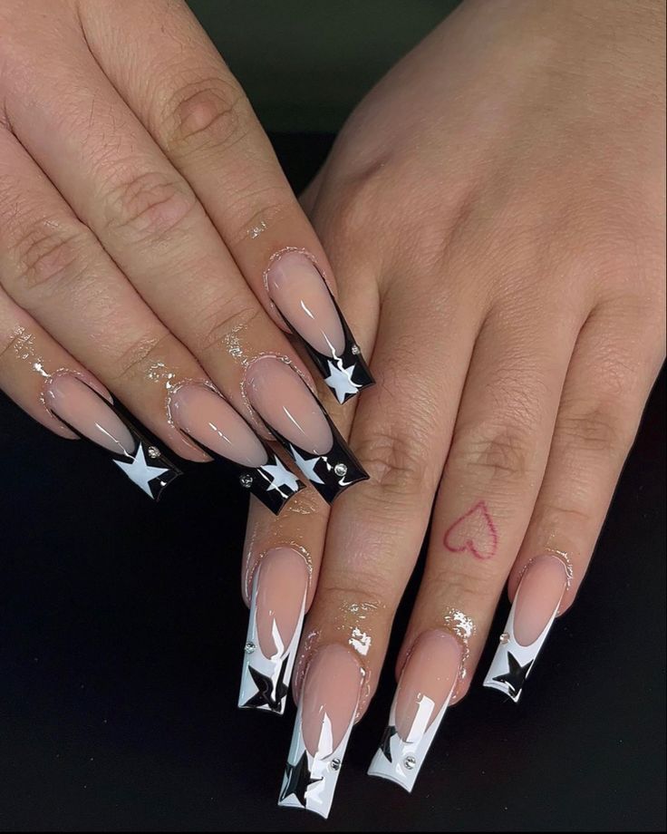 Chic Nail Design: Nude and Bold Black Tips with Star Motifs and Glittering Cuticles.