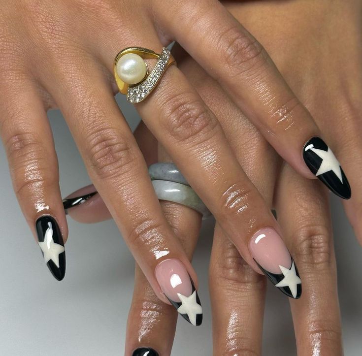 Chic Black and Nude Nail Design with Bold Star Motifs and Elegant Accents.