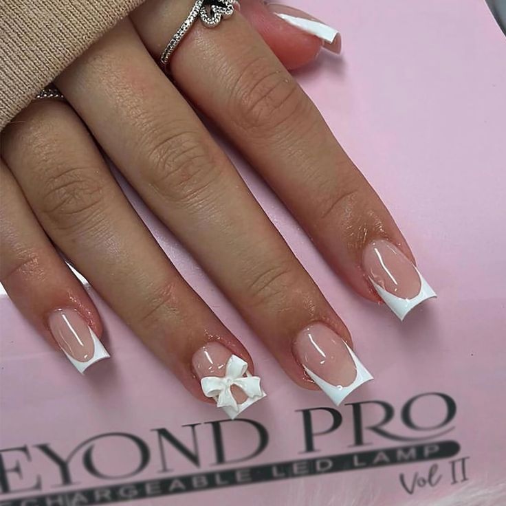 Chic Nude and White French Tip Nails with 3D Bow Accent for Modern Elegance.