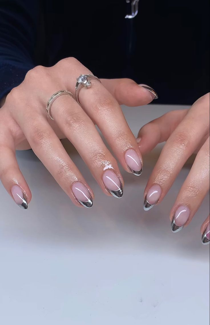 Chic French Manicure with Metallic Tips and Glam Embellishments.