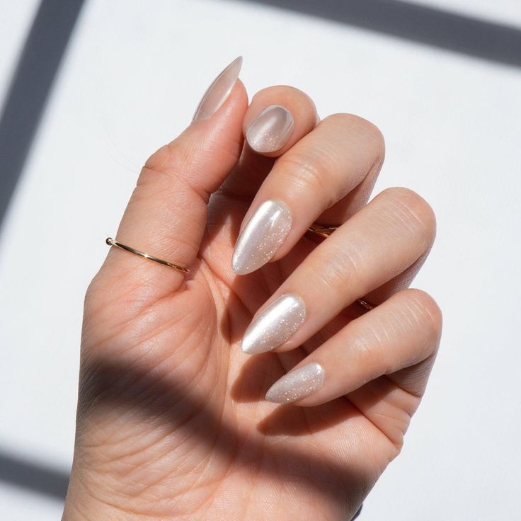 Chic Almond-Shaped Nails with Shimmery Nude Polish and Gold Ring: A Modern Classic.