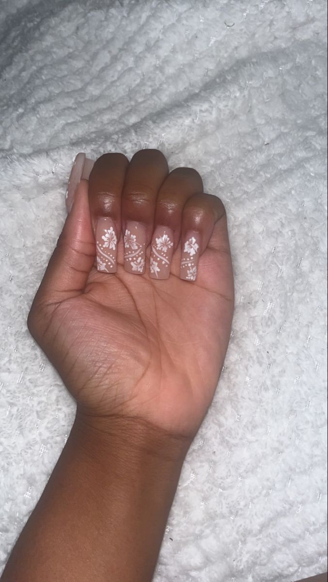 Sophisticated Nude Nail Design with Delicate White Floral Patterns.