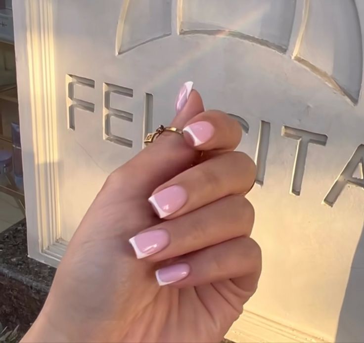 Elegant Soft Pink and White Tip Nail Design with Glossy Finish and Gold Ring Accent.