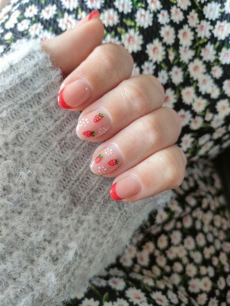 Cheerful Nail Design: French Tips Meet Whimsical Fruit Art with Red Tips and Floral Patterns.