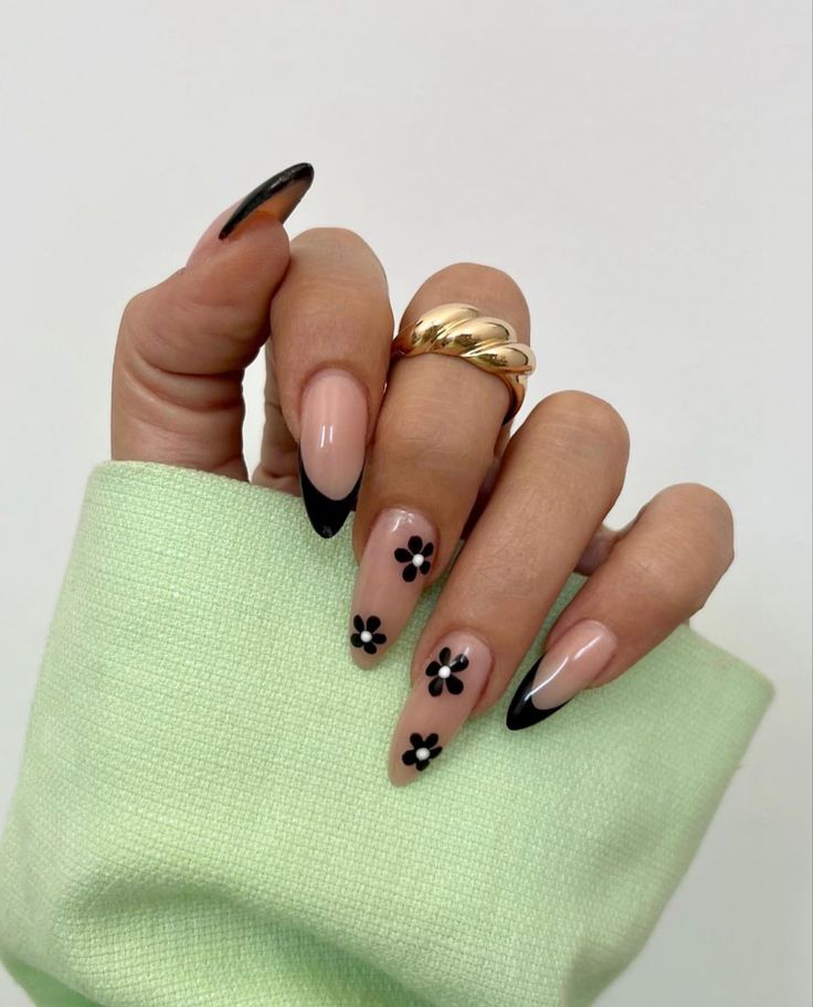 Chic Nude Nail Design with Black Tips and Floral Patterns, Accentuated by a Trendy Gold Ring