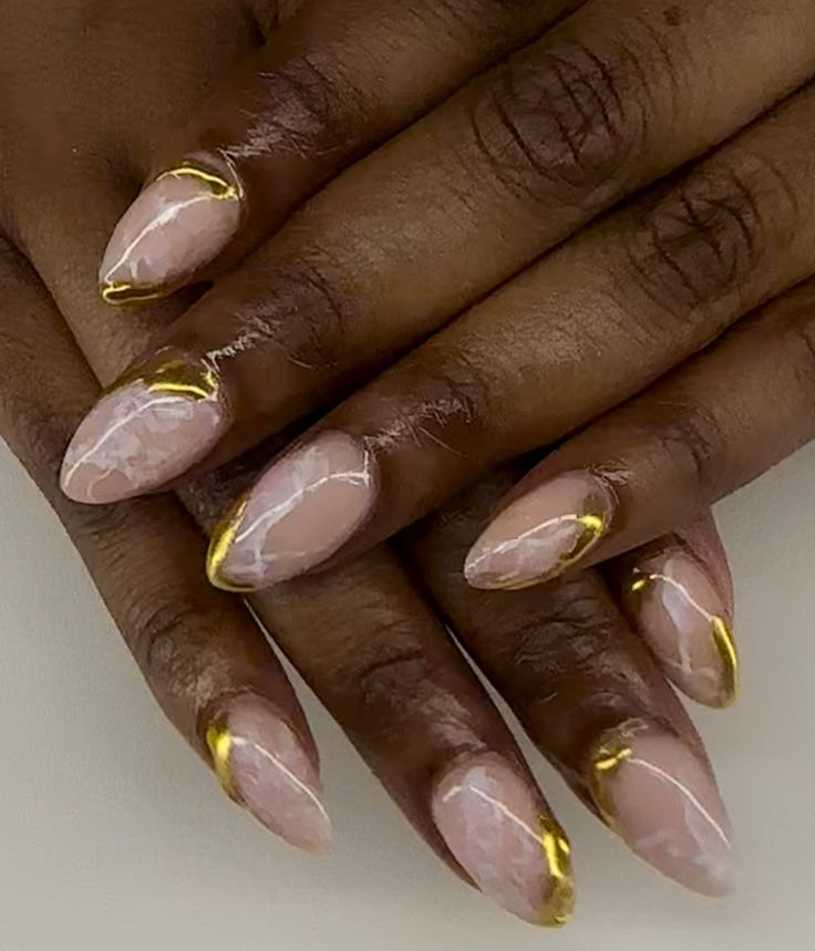 Chic Soft Pink Almond Nail Design with Intricate Marbling and Glamorous Gold Accents.