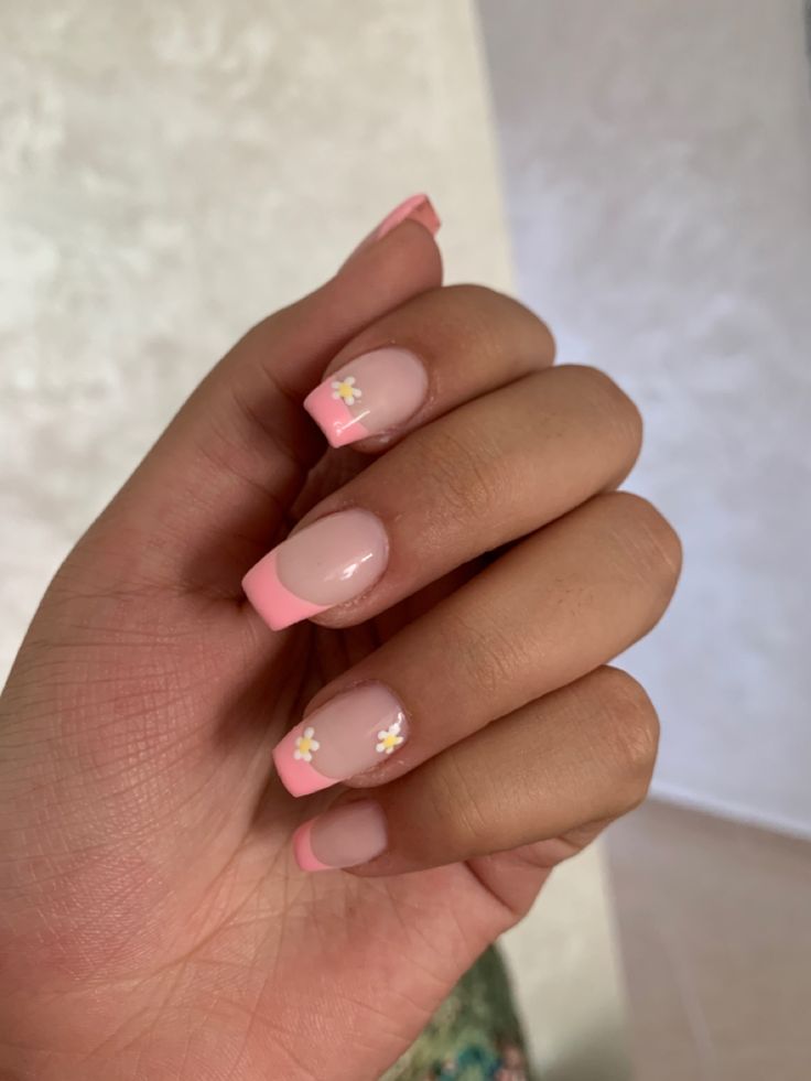 Elegant Soft Pink French Tip Nail Design with Floral Accents for a Feminine Touch.