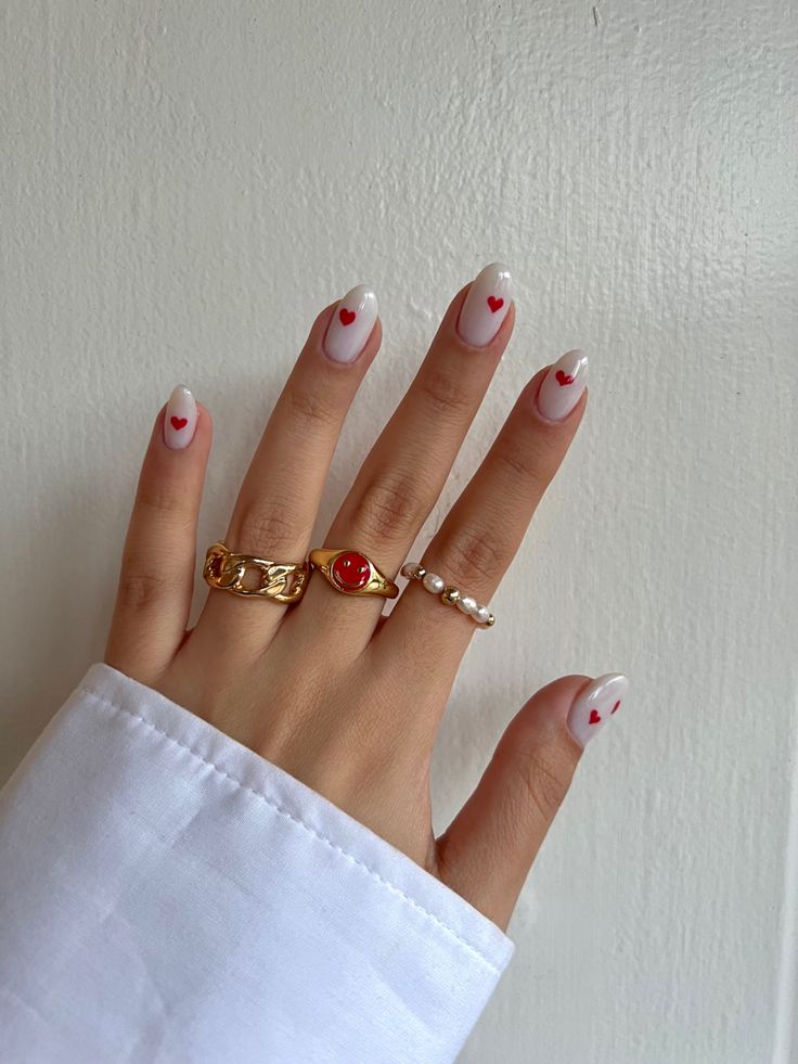 Charming White and Red Heart Nail Design with Elegant Gold and Pearl Accents for Romantic Occasions.