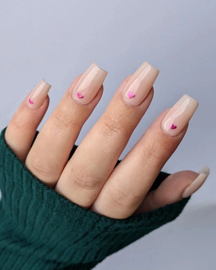 Elegant Nude Nail Design with Subtle Pink Heart Accents for a Sophisticated Yet Playful Look.