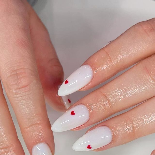 Elegant Almond-Shaped Nails: Glossy White Base with Playful Red Heart Accents.