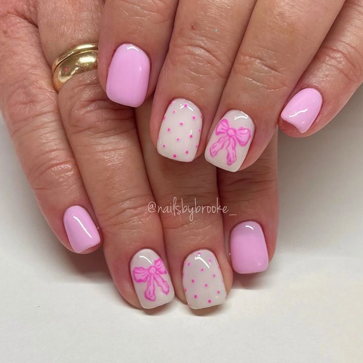 Playful Pink Nail Design with Dotted Patterns and Charming Accent Bows.