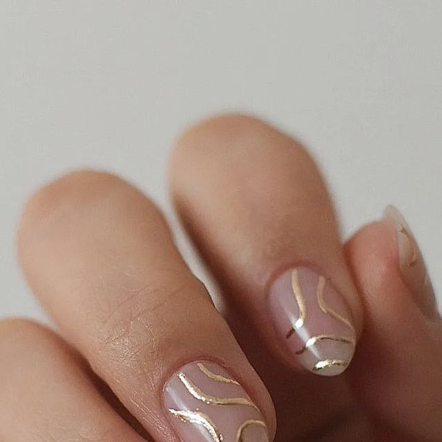 Chic Soft Pink Nail Design with Elegant Gold Swirls.