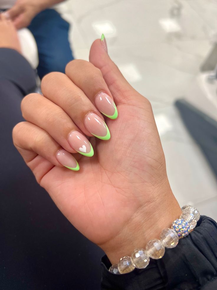 Chic Nail Design: Neutral Base with Vibrant Green Tips and Heart Accents.