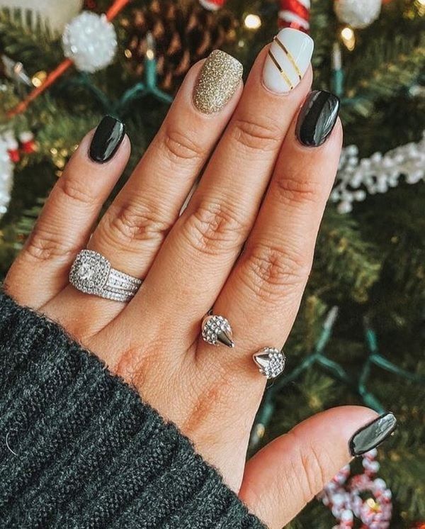 Chic Black and Gold Nail Design with Glittery Accents and Sparkling Rings.