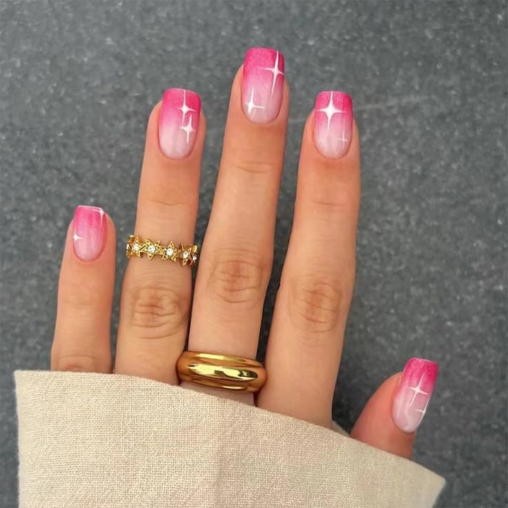 Chic Ombre Nail Design with Soft Pink Shades, Starry White Accents, and Gold Ring Accents.